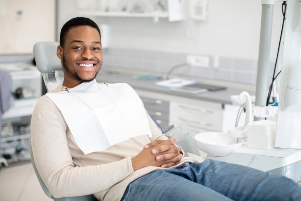 Smiling young Black man in a dental chair with a bib.
