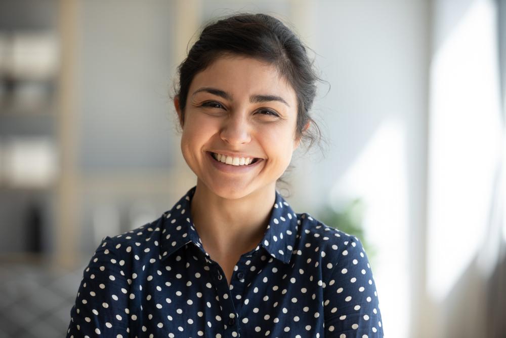 Smiling woman in a navy polka-dot shirt.