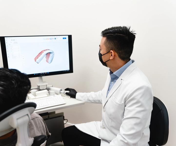 Dr. Julian Huynh shows a patient a 3D dental model on a computer screen.