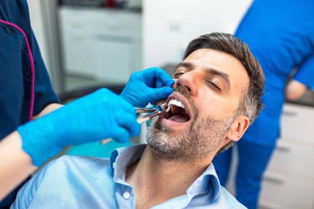 A dentist and patient view a 3D dental model on a computer screen.