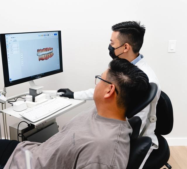 Dr. Julian Huynh and patient viewing a 3D dental scan on a computer.