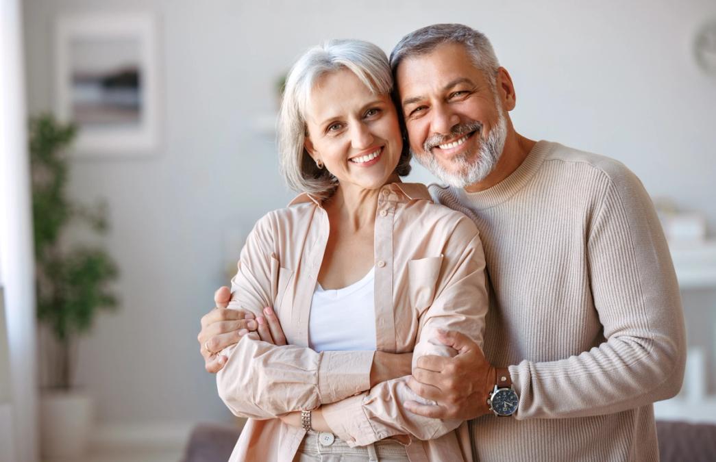 A smiling older couple embracing.