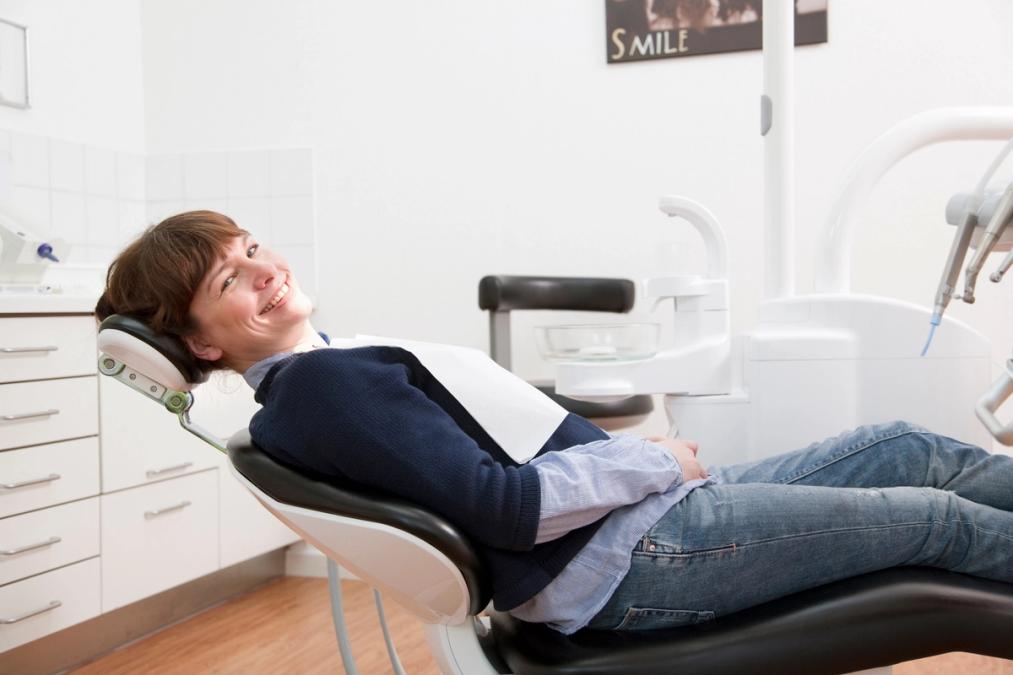A smiling woman in a dental chair.