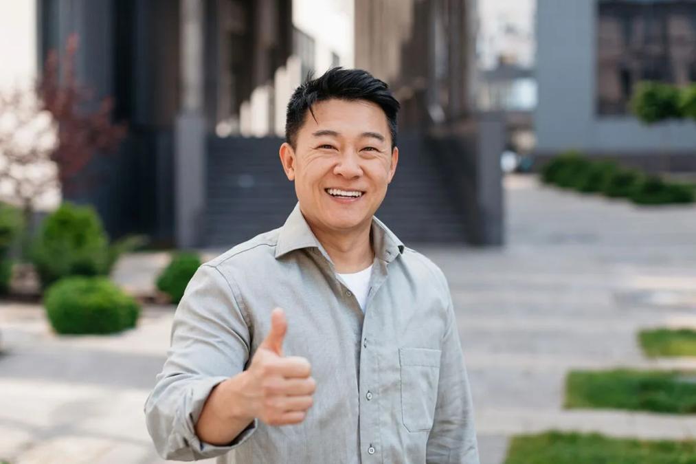Smiling Asian man giving a thumbs-up.