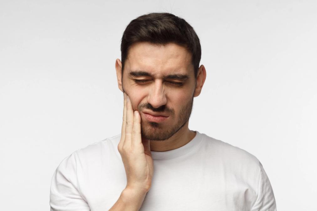 Man holding his cheek with a pained expression.